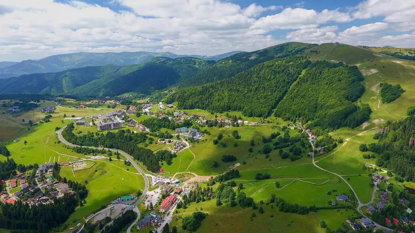 Donovaly z vtáčej perspektívy v lete, zelené svahy a domy v doline