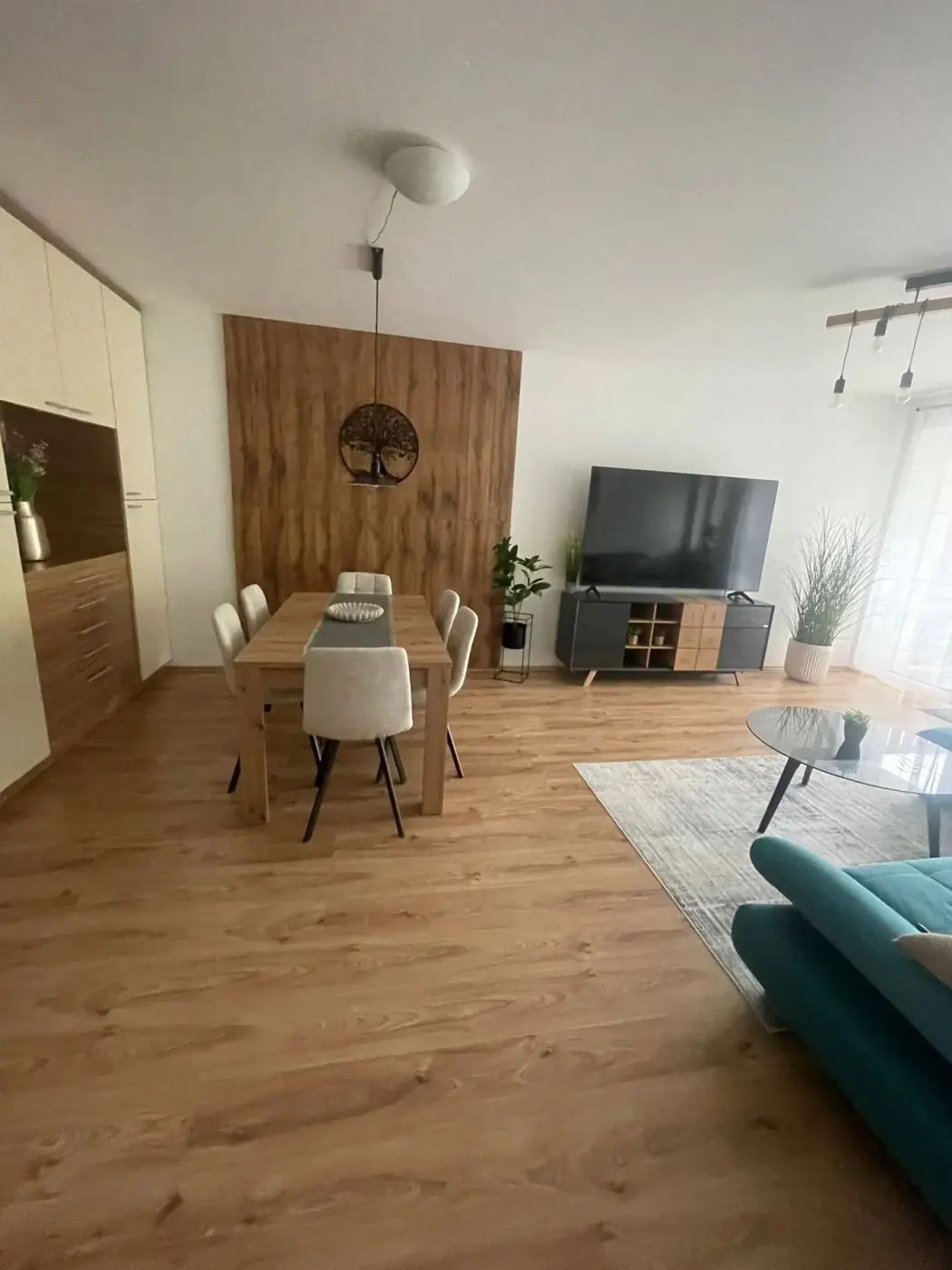 Obývacia časť s jedálenským stolom a dreveným obkladom steny